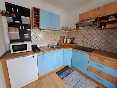 a kitchen with blue cabinets and a microwave at Charming Celje City Center Apartment in Celje