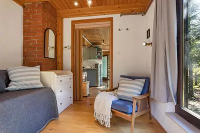 a bedroom with a bed and a chair and a mirror at Cabin by the river Polhov Gradec in Polhov Gradec