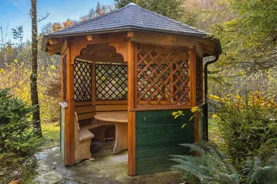 a wooden gazebo with a table in it at Cabin by the river Polhov Gradec in Polhov Gradec