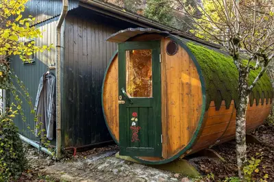 a large wooden barrel house with a green door at Cabin by the river Polhov Gradec in Polhov Gradec
