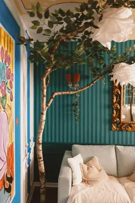 a living room with a tree painted on the wall at Mondo Diverso in Ljubljana