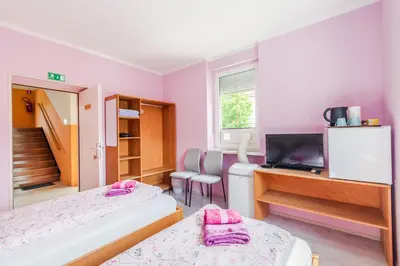 a room with two beds and a desk and a television at Apartments Orhideja in Tolmin