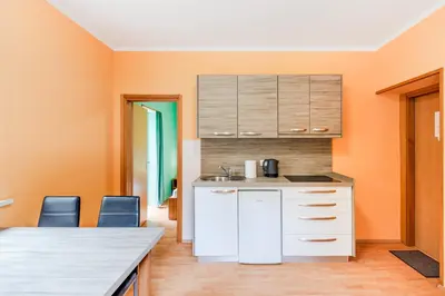 a kitchen with orange walls and a counter and chairs at Apartments Orhideja in Tolmin