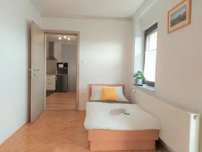 a small bedroom with a bed and a window at Apartments Repinc in Bled