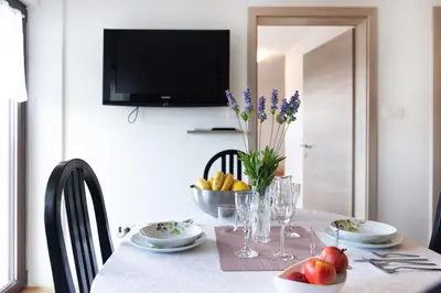 a dining room table with a bowl of fruit and a television at Apartments Repinc in Bled