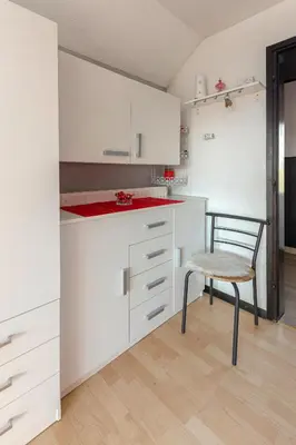 a kitchen with white cabinets and a chair at Oddih ob Krki in Škocjan