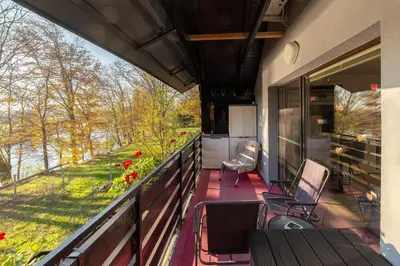 a balcony with chairs and a table and a view of a river at Oddih ob Krki in Škocjan