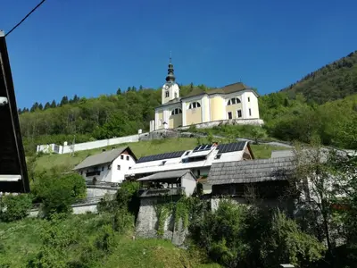 a large white building on a hill with a church at Apartment Ivanka Cvetek in Bohinj