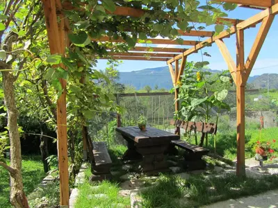 a wooden pergola with a picnic table and benches at Apartment Rakušček in Kobarid