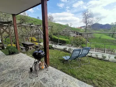 a patio with two chairs and a grill on the grass at Apartment Rakušček in Kobarid