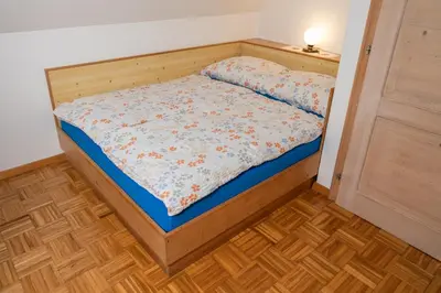 a small bed in a room with a wooden frame at Holiday Home Pri Srni in Bohinj