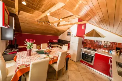 a kitchen with a table and a kitchen with red cabinets at Tami in Lokve