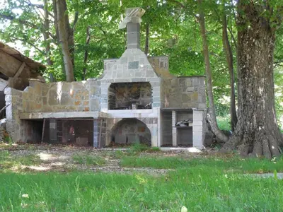 a stone oven sitting in the grass next to a tree at Tami in Lokve