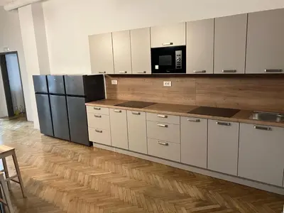 a large kitchen with white cabinets and a microwave at CafDorm in Maribor