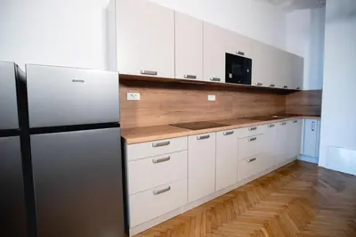 a kitchen with white cabinets and a black refrigerator at CafDorm in Maribor