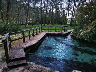 a wooden bridge over a river next to a fence at Hiška sončni hrib. in Novo Mesto