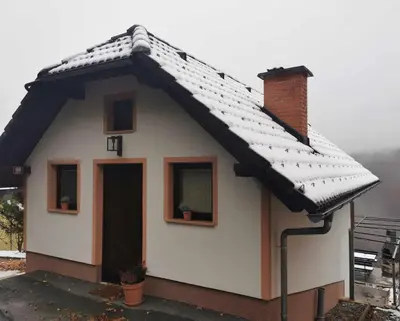 a small house with a snow covered roof at Hiška sončni hrib. in Novo Mesto