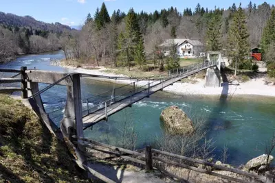 a bridge over a river with a house in the background at Riverhouse apartment in Radovljica