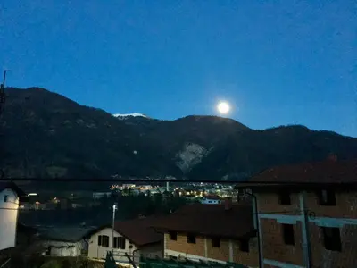 a full moon rising over a mountain range with houses at Apartment Maruška in Tolmin