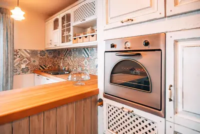 an oven in a kitchen with white cabinets at Posest Kunigunda in Šmartno v Rožni Dolini