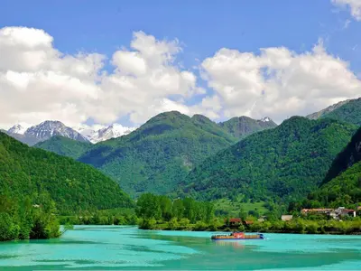 a boat on a river with mountains in the background at Chalet and Apartment Žonir with SAUNA in Kobarid