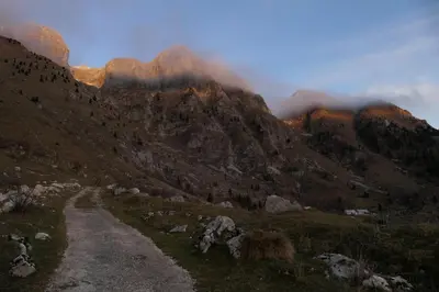 a dirt road through a mountain range with clouds at Apartment Bon in Kobarid