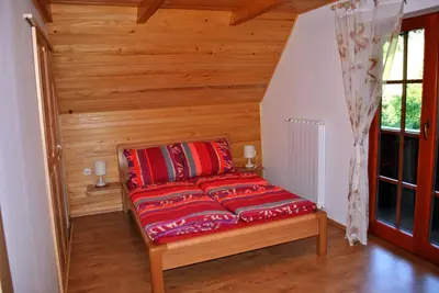 a red couch sitting in the corner of a room at Apartmaji Brložnica pod Veliko planino in Luče