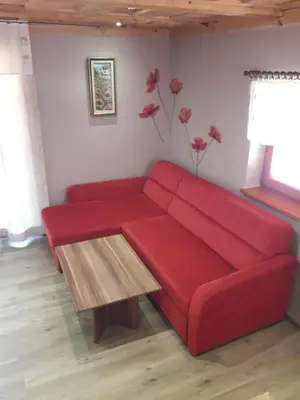 a red couch in a living room with a table at Apartmaji Brložnica pod Veliko planino in Luče
