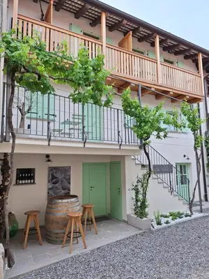 a building with a balcony and two stools and a barrel at Vila Imenja in Šmartno