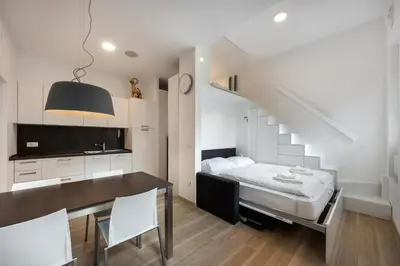 a bedroom with a bed and a dining table and a staircase at Apartma Juniper in Kranjska Gora