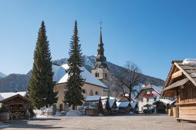 a village with a church and trees in the snow at Apartma Juniper in Kranjska Gora