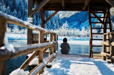 a person sitting on a wooden bridge in the snow at Apartma Juniper in Kranjska Gora