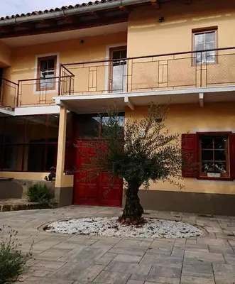 a tree in front of a building with red doors at Kraska nisa in Komen