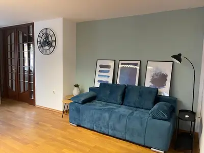a blue couch in a living room with pictures on the wall at Spacious Cozy apartment in Ljubljana