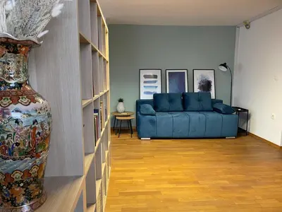 a living room with a blue couch and a vase at Spacious Cozy apartment in Ljubljana