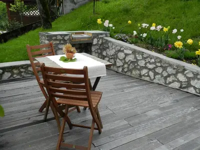 a table and two chairs on a deck with flowers at Apartments Dvor in Bovec