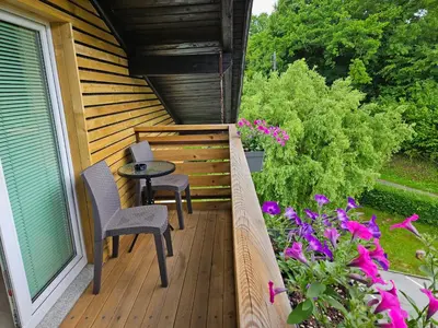 a balcony with a table and chairs and flowers at Apartments Domačija Mlaker in Podčetrtek