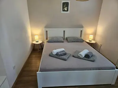 a bedroom with a bed with two lamps on two tables at Apartments Domačija Mlaker in Podčetrtek