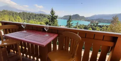 a wooden table with two wine glasses on a balcony at Apartment Milly in Bled
