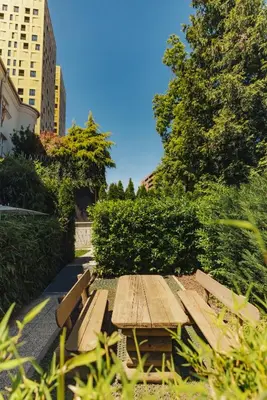 a wooden picnic table in a park with buildings at City Glamping by ONE66 Hotel in Ljubljana