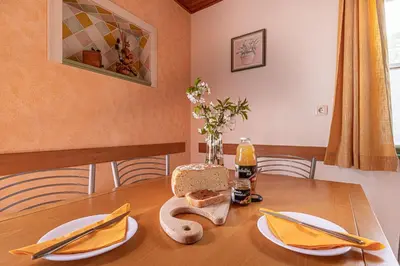 a wooden table with yellow napkins and plates on it at Lukčeva domačija počitniška hiša - Happy Rentals in Kostel