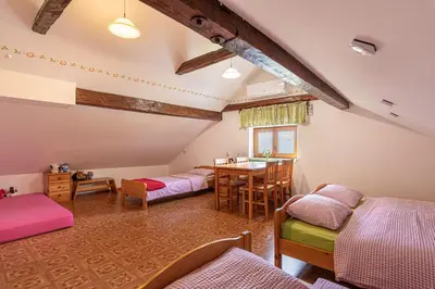 a room with four beds and a table and a dining room at Lukčeva domačija počitniška hiša - Happy Rentals in Kostel