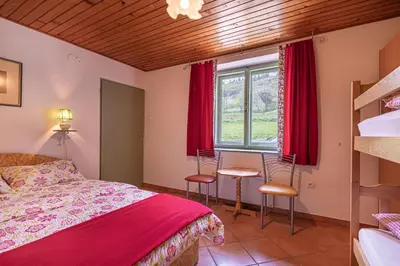 a bedroom with a bed and a window with red curtains at Lukčeva domačija počitniška hiša - Happy Rentals in Kostel