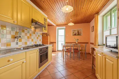 a kitchen with yellow cabinets and a table with chairs at Lukčeva domačija počitniška hiša - Happy Rentals in Kostel