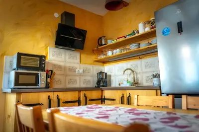 a kitchen with a table and a refrigerator at Stara sončna hiša in Radovljica