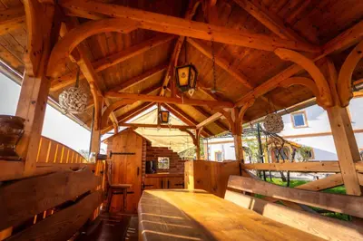 a large wooden room with a wooden table and benches at Stara sončna hiša in Radovljica