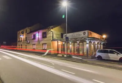 a white car parked in front of a building at night at Guesthouse Živko in Dobrovce