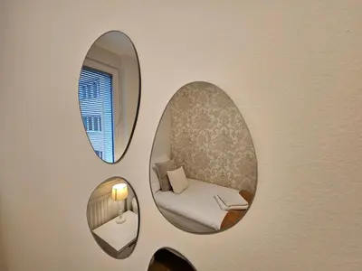 two mirrors on a wall with a chair in a room at Ljubljana Central Suite Martin in the City Center in Ljubljana