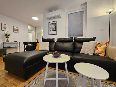 a living room with a black leather couch and two tables at Ljubljana Central Suite Martin in the City Center in Ljubljana