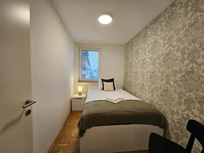 a small bedroom with a bed and a window at Ljubljana Central Suite Martin in the City Center in Ljubljana